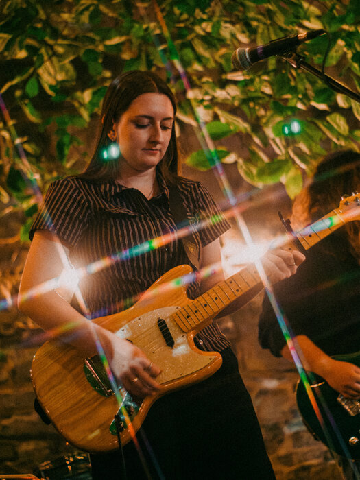 Jessica Wolowich strums an electric guitar on the outdoor patio at Musiikki Caf&eacute;.